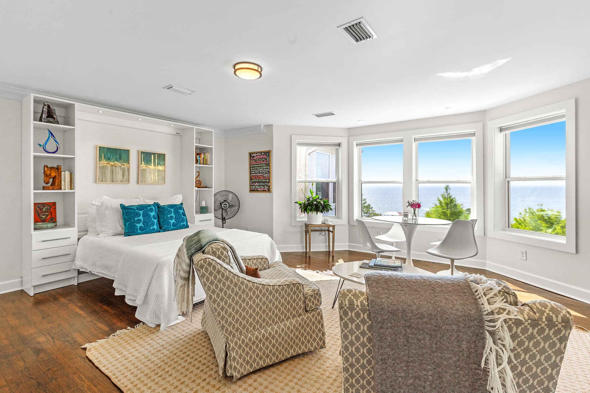Bright and airy bedroom with a large window view, minimalist decor, and cozy seating areas.