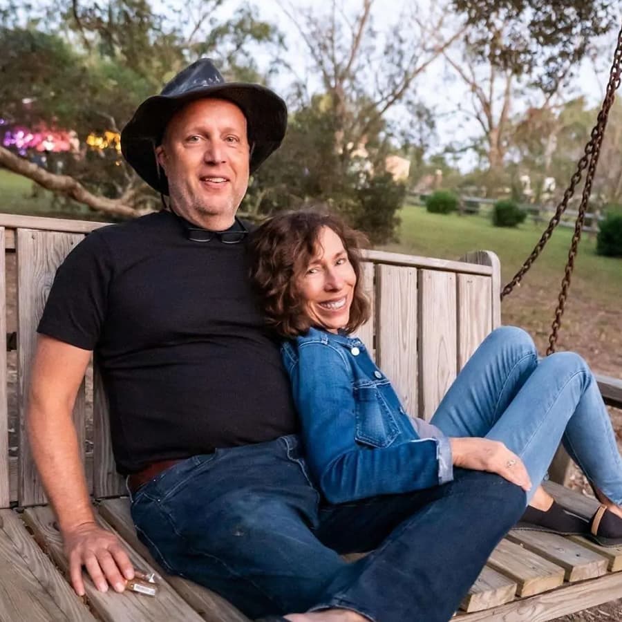 A smiling man and a woman on a wooden porch swing